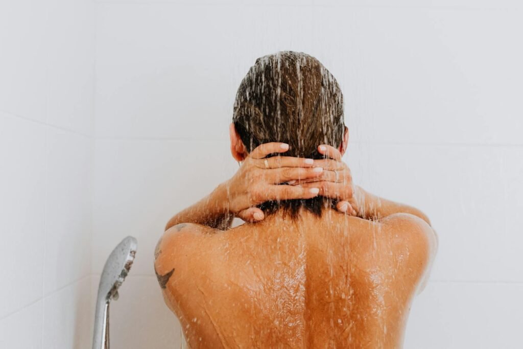 Rear view of a woman enjoying a fresh shower, water streaming down her back.